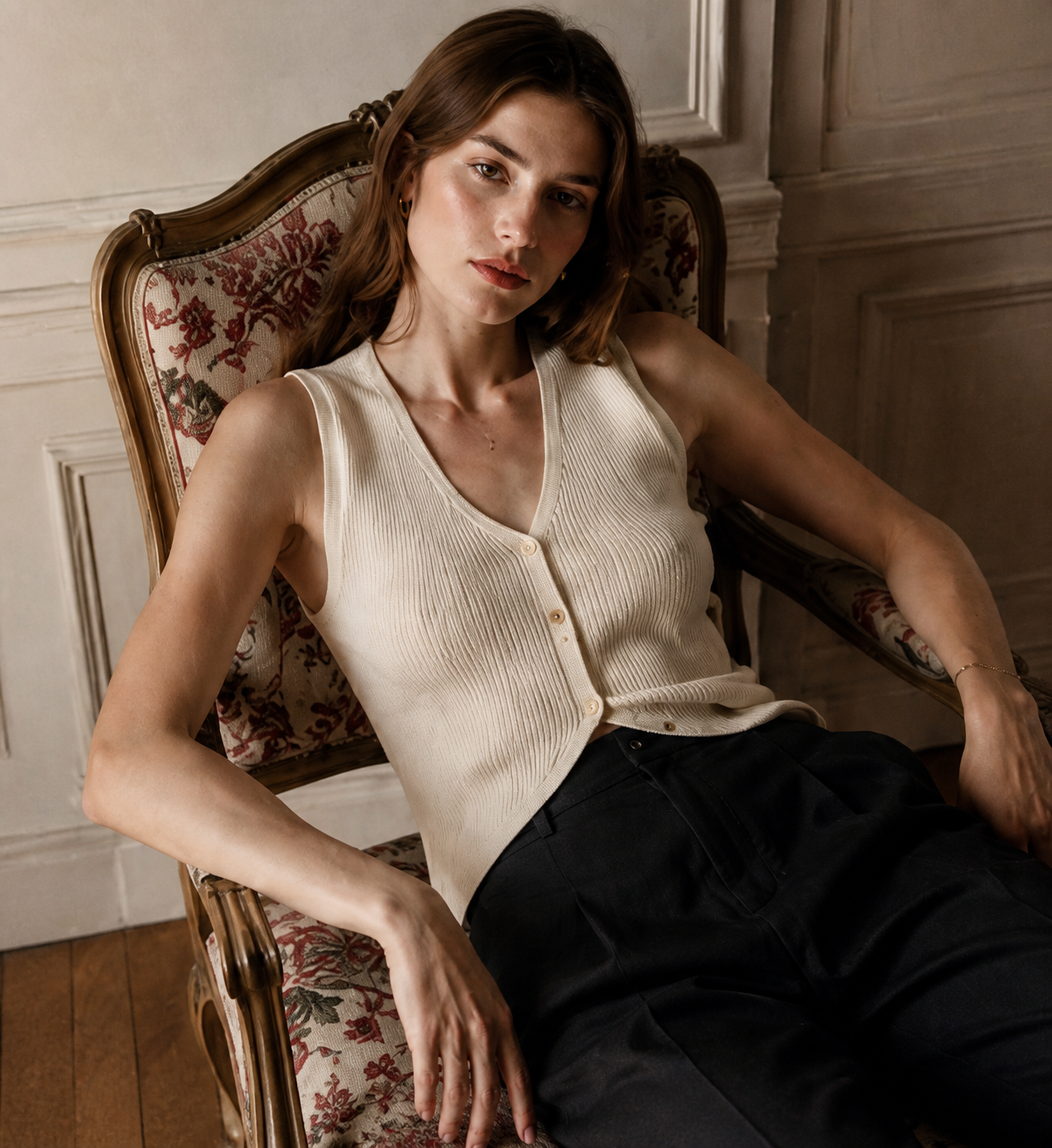 Woman wearing an ivory ribbed button vest and black tailored trousers